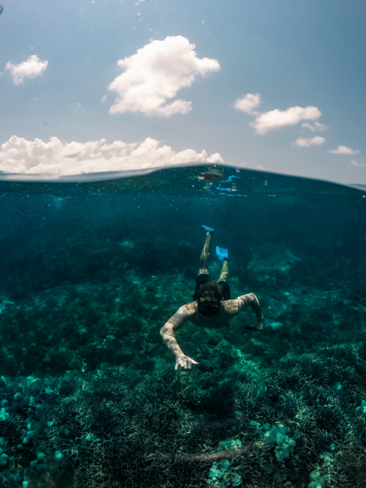 vertical-shot-male-swimming-underwater-with-sky-background